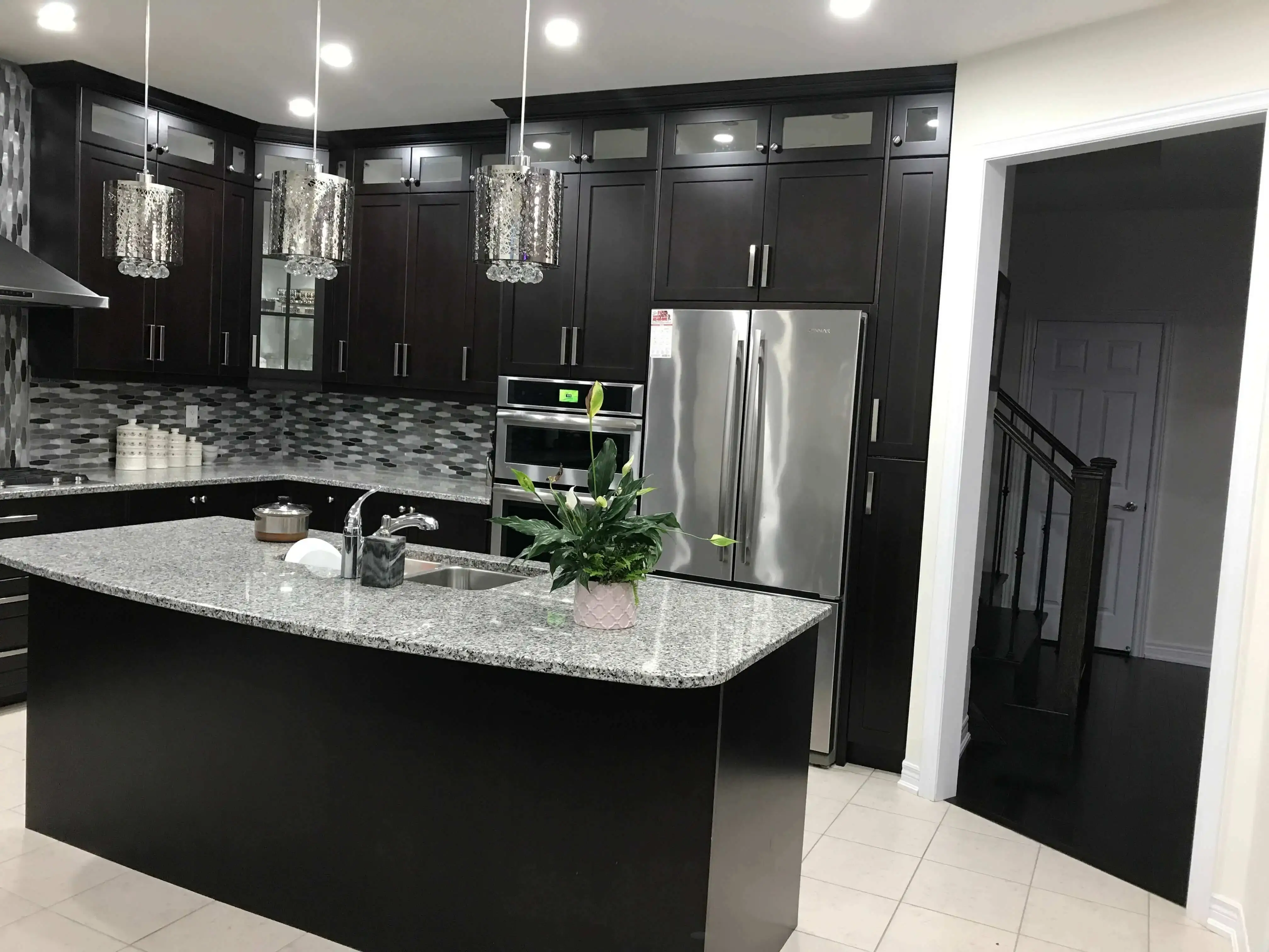 Espresso kitchen with glass-front uppers, crystal pendants and a granite island