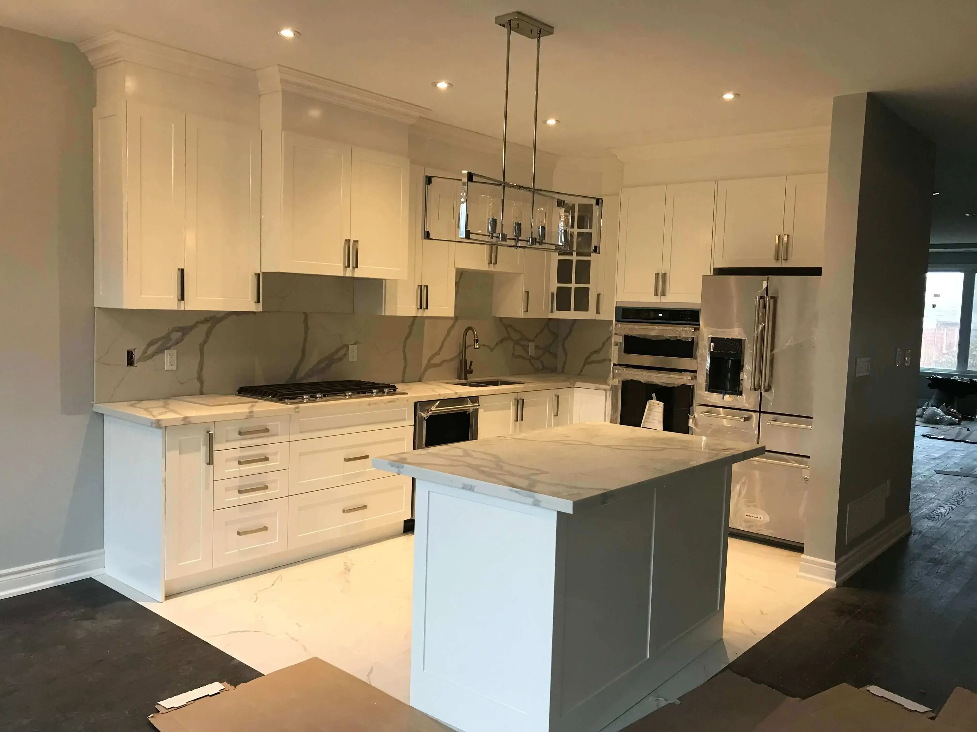White shaker kitchen with a marble-look island and full-height backsplash